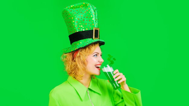 Donna sorridente con cappello verde che beve birra festa del pub del giorno di patrizio che celebra la tradizione irlandese