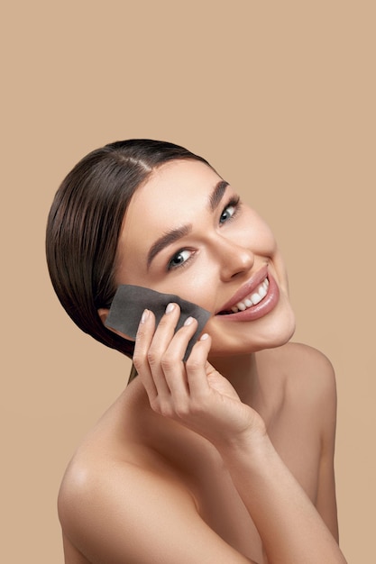 Donna sorridente con carta assorbente olio facciale Primo piano del bellissimo modello con trucco naturale