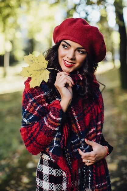 Donna sorridente con foglia d&#39;autunno