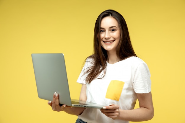donna sorridente con il portatile su sfondo giallo