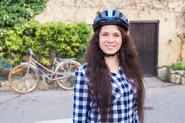 Donna sorridente con la posizione del casco su sfondo bicicletta e vicolo