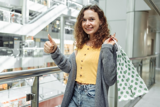 Donna sorridente con le borse della spesa al centro commerciale