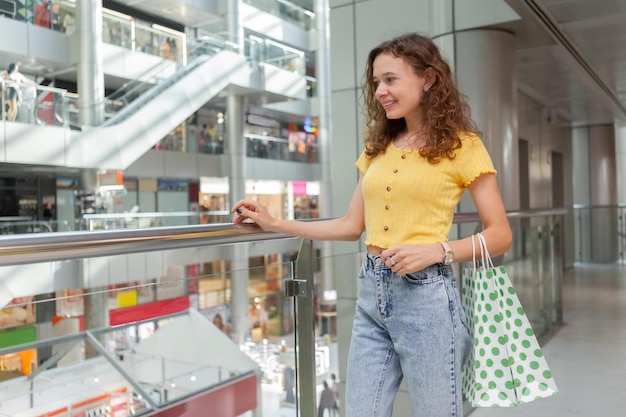 Donna sorridente con le borse della spesa al centro commerciale