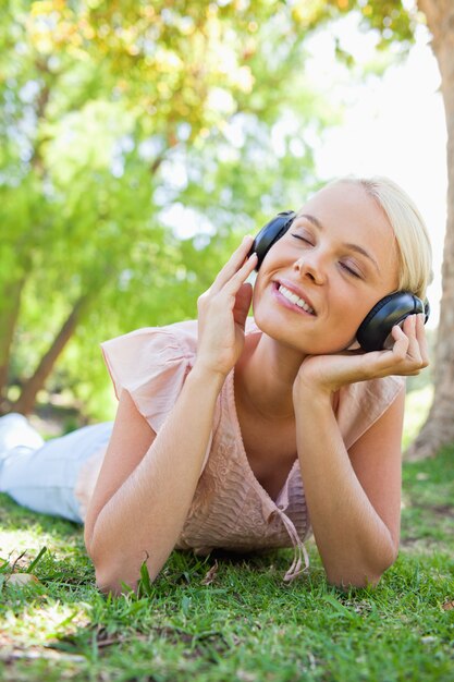 Donna sorridente con le cuffie che godono della musica sul prato inglese