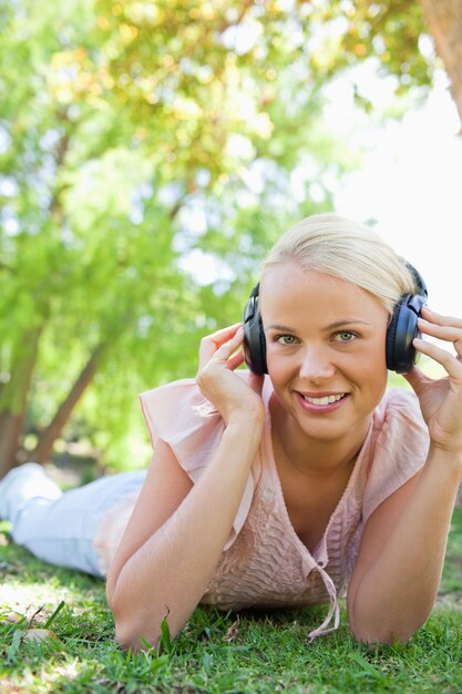 Donna sorridente con le cuffie che godono della musica sull&#39;erba