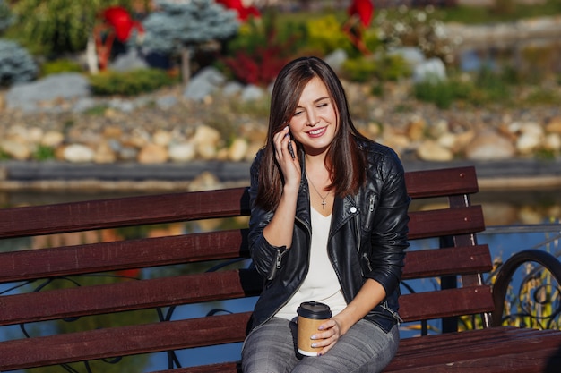 Donna sorridente con lo smartphone che si siede nel parco