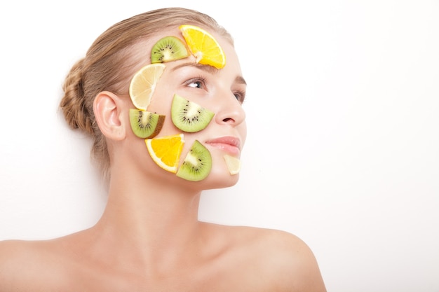 Donna sorridente con maschera di frutta sul viso isolata