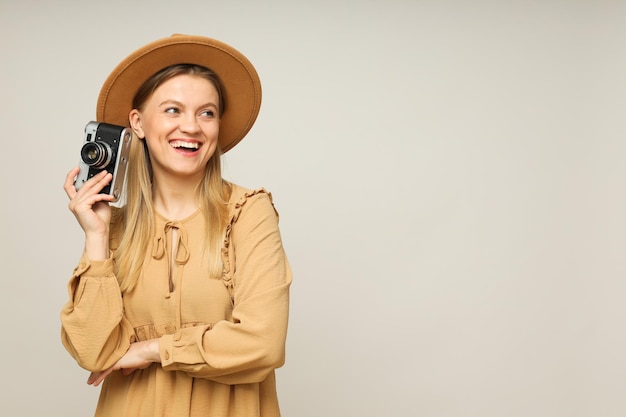 Donna sorridente con un cappello con una telecamera vintage su uno spazio di sfondo chiaro per il testo