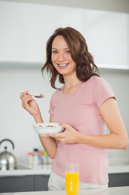 Donna sorridente con una ciotola di cereali in cucina