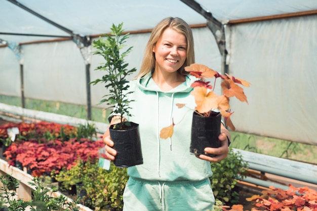 donna sorridente con vasi di fiori all'interno della serra