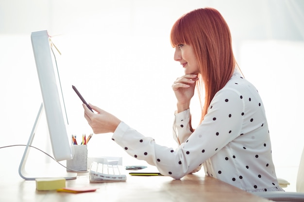 Donna sorridente dei pantaloni a vita bassa che indica schermo con la penna