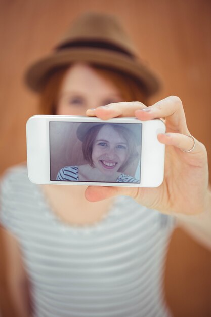 donna sorridente dei pantaloni a vita bassa che prende un selfie