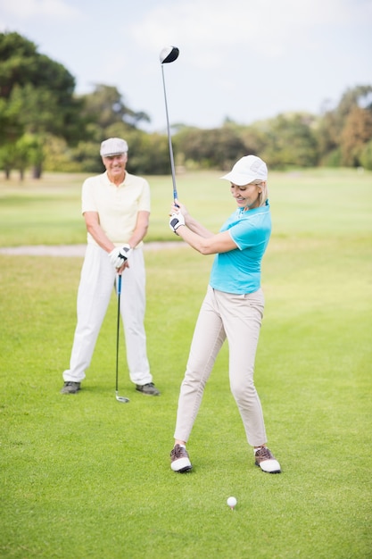 Donna sorridente del giocatore di golf che prende colpo