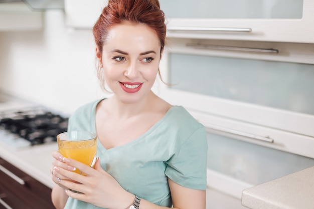 Donna sorridente del ritratto che beve il succo di arancia