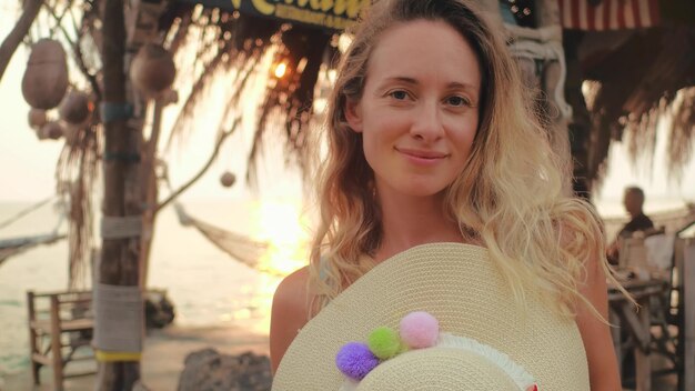 Donna sorridente del ritratto sull'amaca della spiaggia del fondo che esamina macchina fotografica