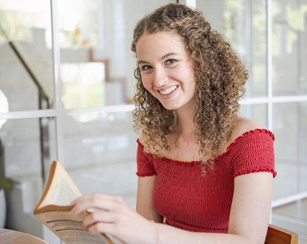 Donna sorridente della bella ragazza che legge un libro a casa Libro di lettura di concetto di studio