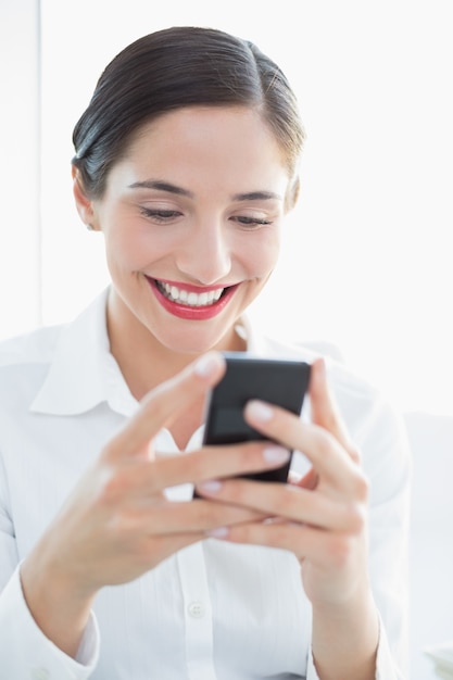 Donna sorridente di affari che esamina telefono mobile