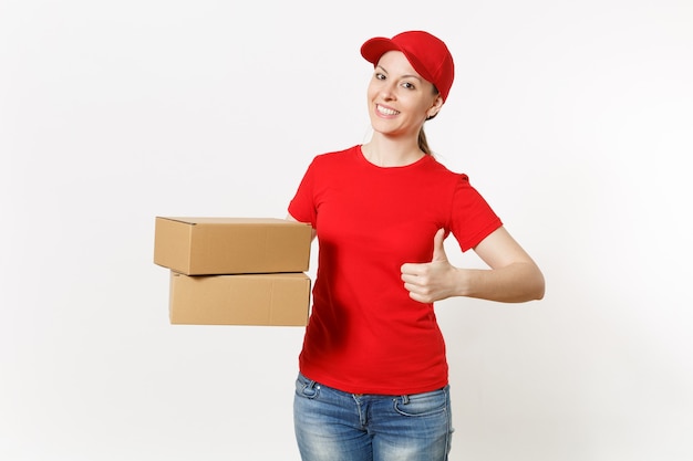 Donna sorridente di consegna in uniforme rossa isolata su fondo bianco. Donna in berretto, t-shirt, jeans che lavora come corriere o rivenditore con scatole di cartone. Ricezione pacco. Copia spazio per la pubblicità.