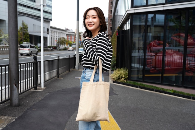 Donna sorridente di scatto medio con borsa in tessuto