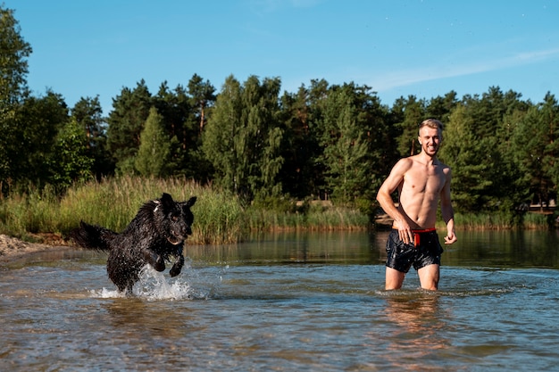 Donna sorridente di vista frontale con il cane alla spiaggia