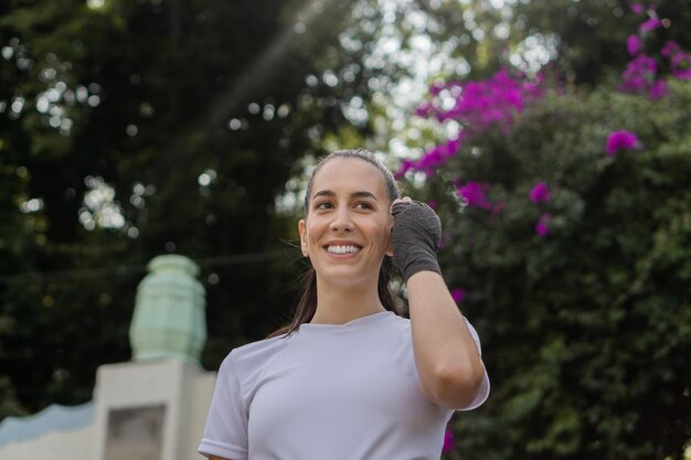 Donna sorridente e camminare in un parco parlando al telefono e indossando cuffie wireless. Copia spazio