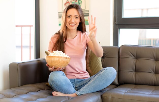 Donna sorridente e dall'aspetto amichevole, mostrando il numero tre o terzo con la mano in avanti, il conto alla rovescia