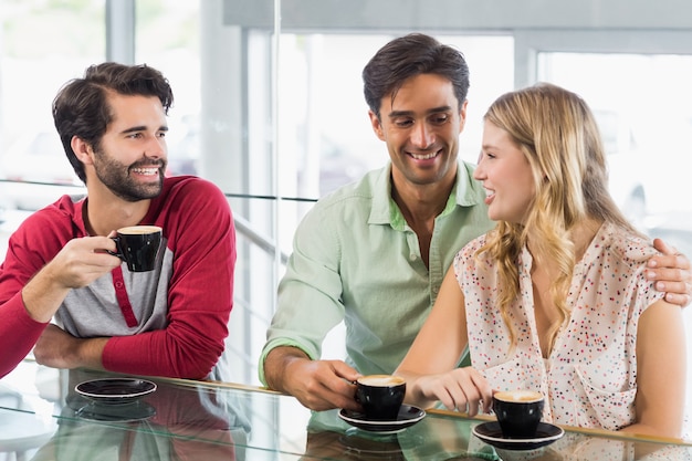 Donna sorridente e due uomini che mangiano tazza di caffè