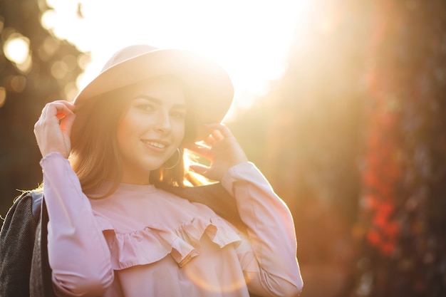 Donna sorridente emotiva con un cappello da portare di trucco naturale, godendosi il caldo clima autunnale. Spazio per il testo