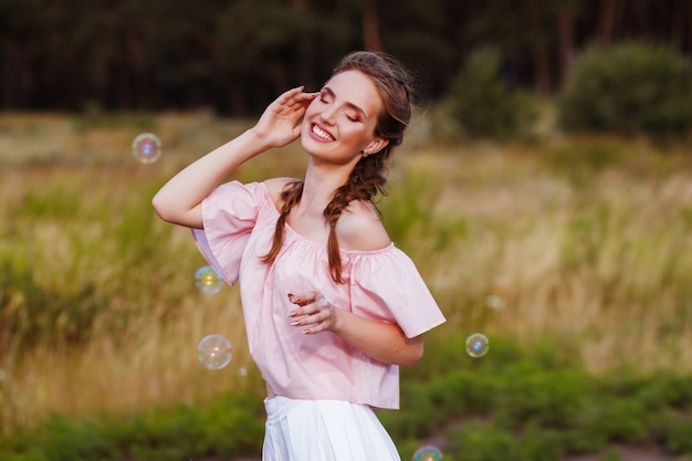 donna sorridente felice con bolle di sapone in estate