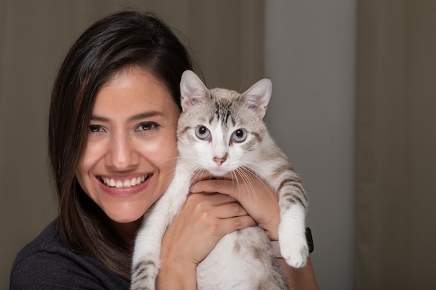 Donna sorridente felice e il suo gatto a strisce bianco con guardando la telecamera in posa per una foto