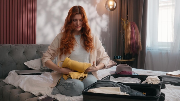 Donna sorridente felice ragazza donna in camera da letto hotel prepararsi per il viaggio vacanza viaggio viaggio turismo