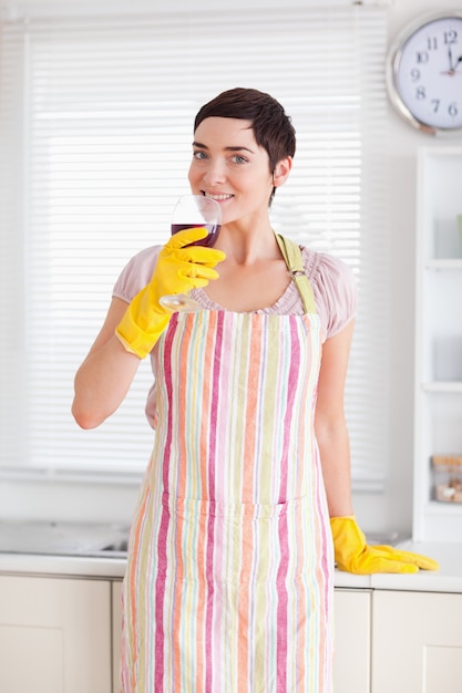Donna sorridente in abito di pulizia con vino