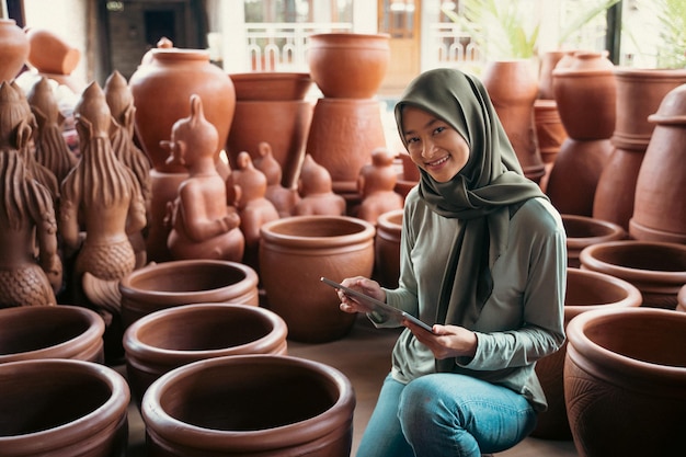 Donna sorridente in hijab che tiene un tampone tra la terracotta