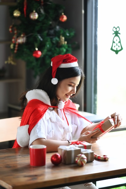 Donna sorridente in regalo di Natale della tenuta del cappello della Santa.