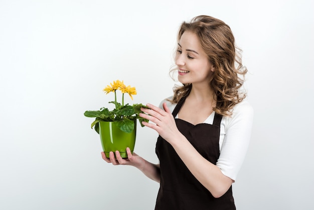 Donna sorridente in vaso da fiori di fioritura della tenuta del grembiule isolato