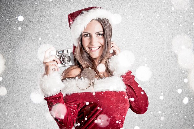 Donna sorridente in vestiti di Babbo Natale con la macchina fotografica