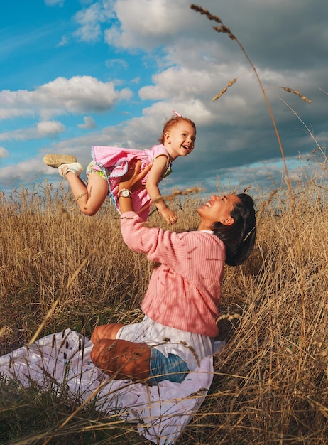 Donna sorridente latina che gioca con la sua piccola figlia rossa