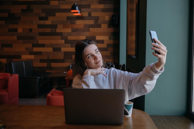 Donna sorridente seduta sul divano della cucina che parla in videochiamata che si incontra online guardando il telefono