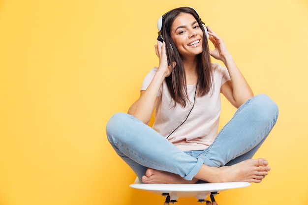 Donna sorridente seduta sulla sedia con auricolare sul muro giallo yellow