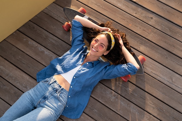 Donna sorridente spensierata su skateboard skateboarder ragazza alla moda rilassata e felice sdraiato su longboard