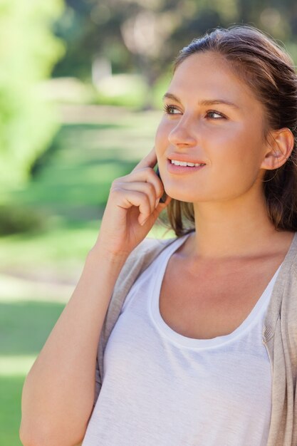 Donna sorridente sul suo telefono cellulare nel parco