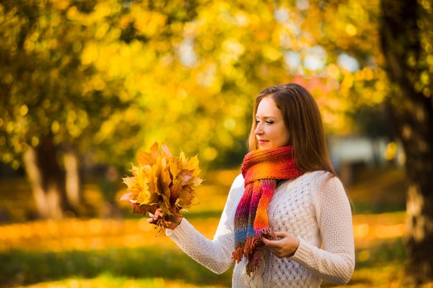 Donna sorridente sveglia che tiene le foglie di acero di autunno