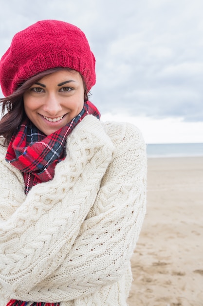 Donna sorridente sveglia in vestiti caldi alla moda sulla spiaggia