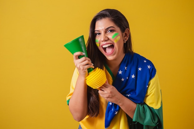 Donna sostenitrice del campionato di calcio 2022 della Coppa del mondo del Brasile utilizzando la bandiera del Brasile come copertura suonando il clacson e festeggiando alla partita di calcio Horn