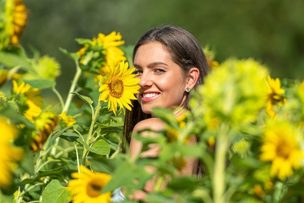 donna sottile sensuale con i capelli lunghi in un campo di girasoli in una soleggiata giornata estiva