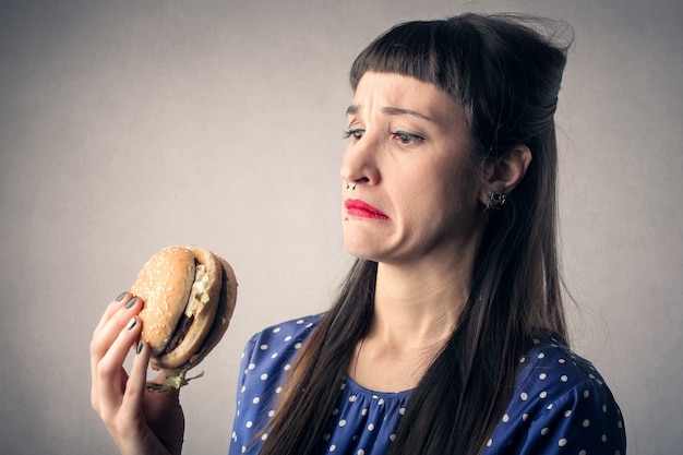 donna spaventata con un grosso hamburger