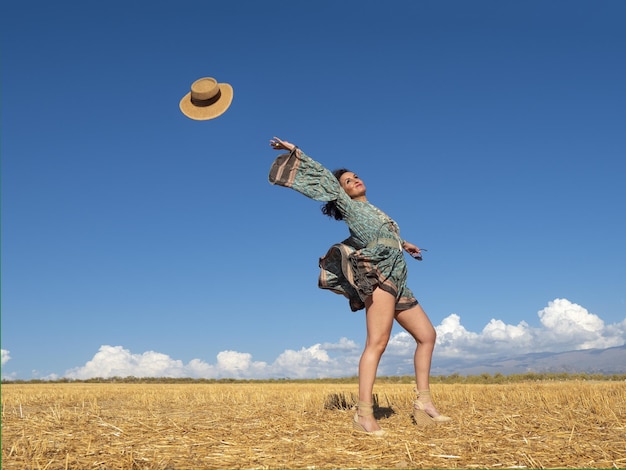 Donna spensierata che lancia il cappello nel campo