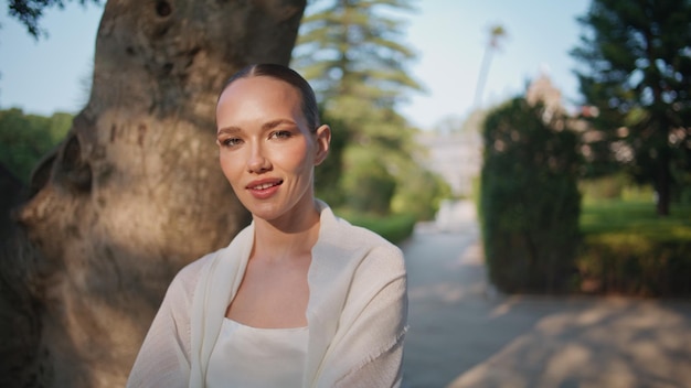 Donna spensierata che si rilassa nel giardino guardando una telecamera in primo piano ritratto di una ragazza sorridente