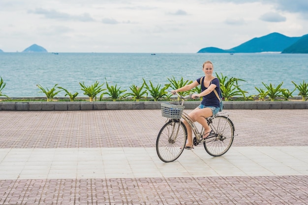 Donna spensierata con la bicicletta in riva al mare divertendosi e sorridendo.