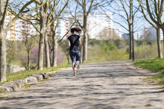 Donna sportiva adulta che pareggia nella vista posteriore del parco